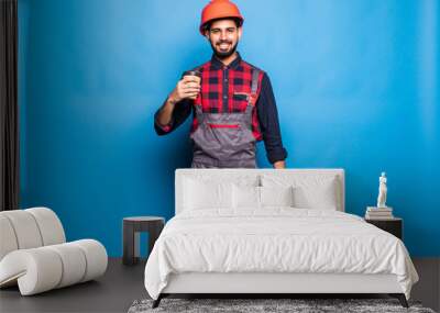 Portrait of indian man holding a red tool box isolated on blue background Wall mural